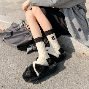 Close-up of wool socks with number 5 embroidery and fluffy faux fur slippers on stairs
