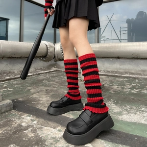 Detail of red and black striped knitted leg warmers with ruffled edges and punk aesthetic
