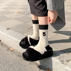 Close-up of black fuzzy slippers with camellia embroidery wool socks and number 5 detail