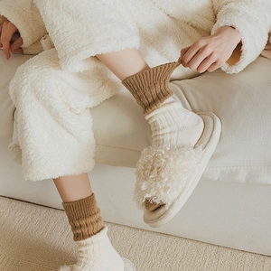 Cozy home setting showing wool socks with color blocking and plush slippers