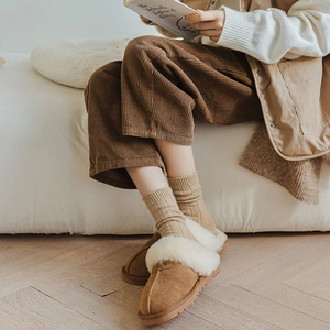 Close-up of brown suede slippers with white faux fur lining and warm wool socks