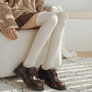 Close-up of off-white wool over-knee socks with vertical knit texture and brown shoes