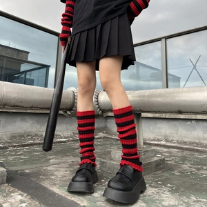 Detailed knit texture of red and black striped leg warmers with ruffle edge