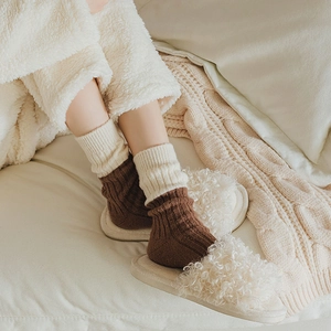 Detailed knit texture of contrast wool socks with plush white home slippers in a cozy setting