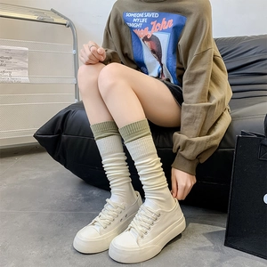 Detail of white slouch socks with green ribbed cuffs paired with platform shoes