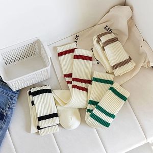 Close-up of four pairs of cream-colored ribbed knee-high socks with college-style stripes