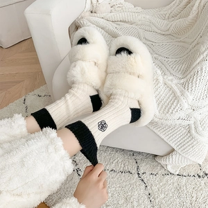 Detail of wool socks with camellia embroidery and plush faux fur home slippers