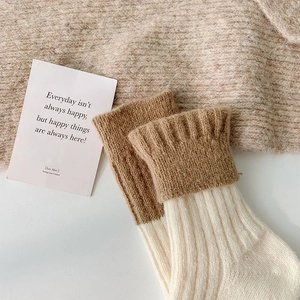 Detail of wool socks featuring brown ribbed cuffs and beige textured knit fabric