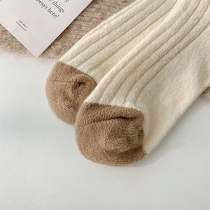 Close-up of thick rib-knit wool socks featuring a contrast toe and warm cream texture