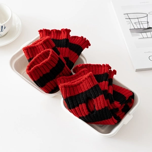 Detail of red and black striped knitted leg warmers with wavy edges in a cozy gift box