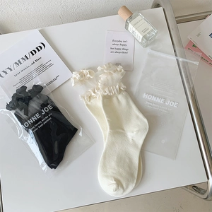 Détail de chaussettes en dentelle beige et noire avec bords à volants superposés chic
