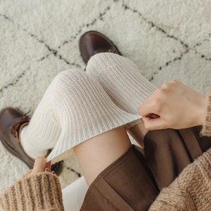 Detail of cream white ribbed knit over-knee socks showing soft wool texture and elasticity