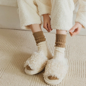 Close-up of cozy white faux fur open-toe slippers paired with striped wool socks