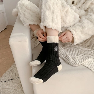 Close-up of wool socks with white rose embroidery and contrast black and white design