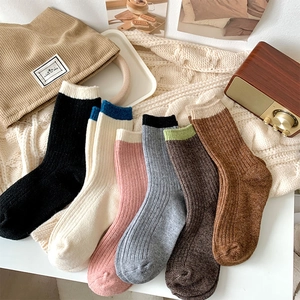 Detailed knit texture of six colorful wool blend socks in a cozy home setting