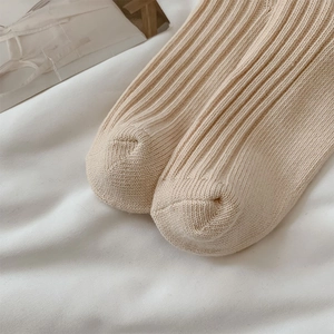 Detailopname van de dikke geribbelde breistructuur en teen van beige katoenen sokken