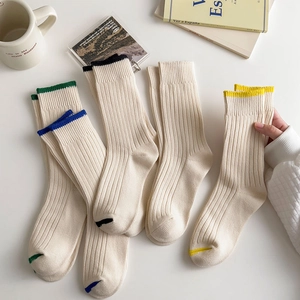 Detailed view of white ribbed mid-calf socks with colorful contrasting trim edges