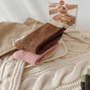 Detailed close-up of ribbed knit crew socks with cream trim in warm brown and pink tones