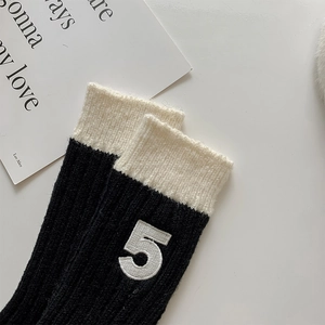 Detail of ribbed knit wool socks featuring a white contrast cuff and number five embroidery