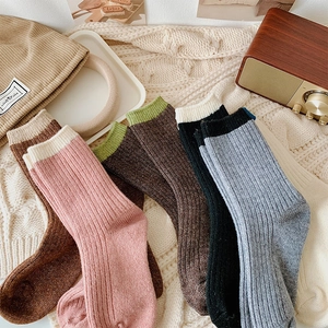 Close-up of ribbed knit wool socks in various colors with a cozy winter home background