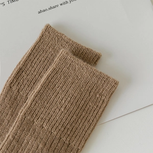Macro detail of thick ribbed wool knit texture and clean hem on a brown knee-high sock