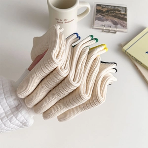 Detailed texture of off-white ribbed knit socks with colorful striped cuffs for women
