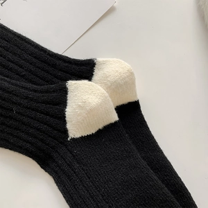 Close-up of winter wool socks featuring black and white contrast knit and ribbed texture