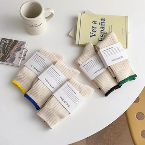 Set of five cream white knitted crew socks with colorful striped cuffs and premium paper bands