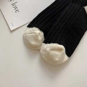 Close-up of black and beige wool socks with thick vertical knit texture and toe detail