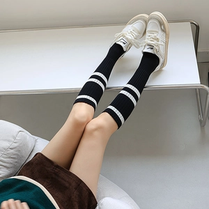 Detail of ribbed cotton knee-high socks featuring white stripes on black fabric