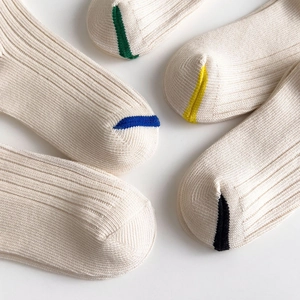 Detailed close-up of ribbed cotton crew socks in off-white with colorful heel and toe accents