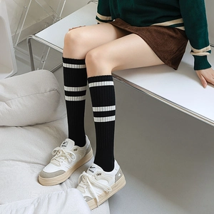 Close-up of black thigh-high socks with double white stripes and ribbed knit texture