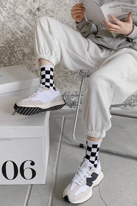 Detail shot of black and white checkerboard crew socks paired with retro sports sneakers
