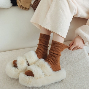 Pantofole bianche a doppia fascia e calze di lana marroni per il comfort invernale in casa