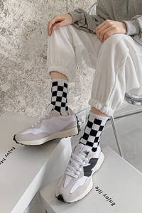 Close-up of stylish black and white checkerboard crew socks paired with retro sneakers