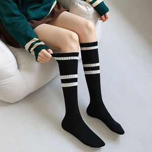 Detail of black ribbed over-the-knee socks featuring white stripes and knit texture
