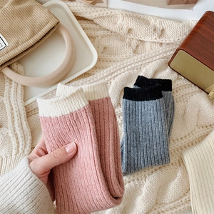 Detail of cozy ribbed knit wool socks in pink and cream on a warm winter blanket