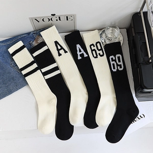 Détail de six paires de chaussettes montantes noir et blanc à rayures et broderie lettrée