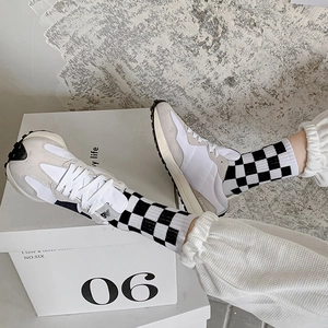 Close-up of retro checkered crew socks styled with cream suede athletic sneakers