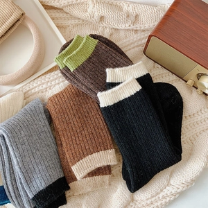 Flat lay of ribbed wool socks in mixed colors on a cozy knitted blanket background