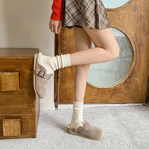 Close-up of tan suede mule slippers with thick faux fur lining and vintage metal buckle