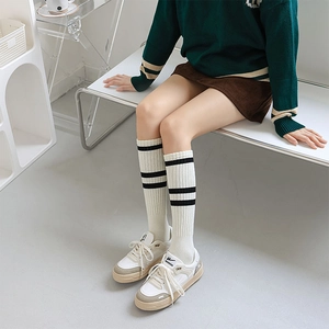 Detail of white knee-high socks with black stripes and vertical ribbed texture