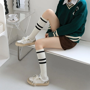 Detail of white rib-knit knee-high socks with classic black double stripes in preppy style