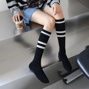 Gros plan de chaussettes montantes noires à rayures blanches sur un escalier