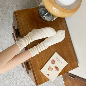 Detailed knit texture of cream mid-calf socks with vintage ribbed cuffs and soft cotton fabric