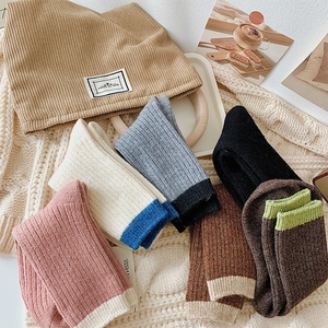 Detail showing colorful ribbed wool socks and knit hat in a warm winter home setting