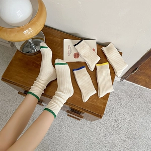 Detail of ribbed knit cotton mid-calf socks with colorful striped cuffs in cream white