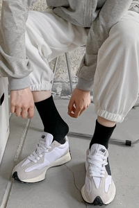 Detail of black mid-calf socks paired with New Balance sneakers and waffle sweatpants