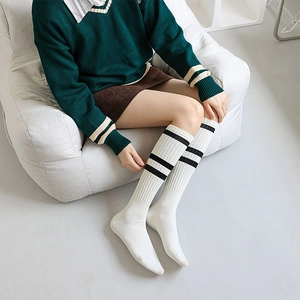 Detail of cream white knee-high socks featuring black twin stripes and ribbed cotton texture