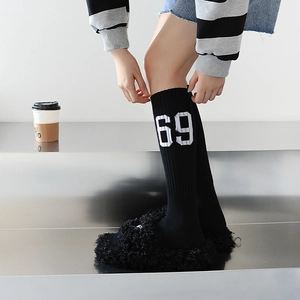 Détail de chaussettes noires tricotées avec chiffre 69 et chaussons en polaire douce